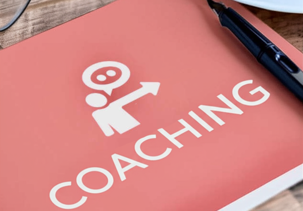 Auf einem Tisch steht eine Tasse Kaffe, eine Brille und ein Consulting Buch