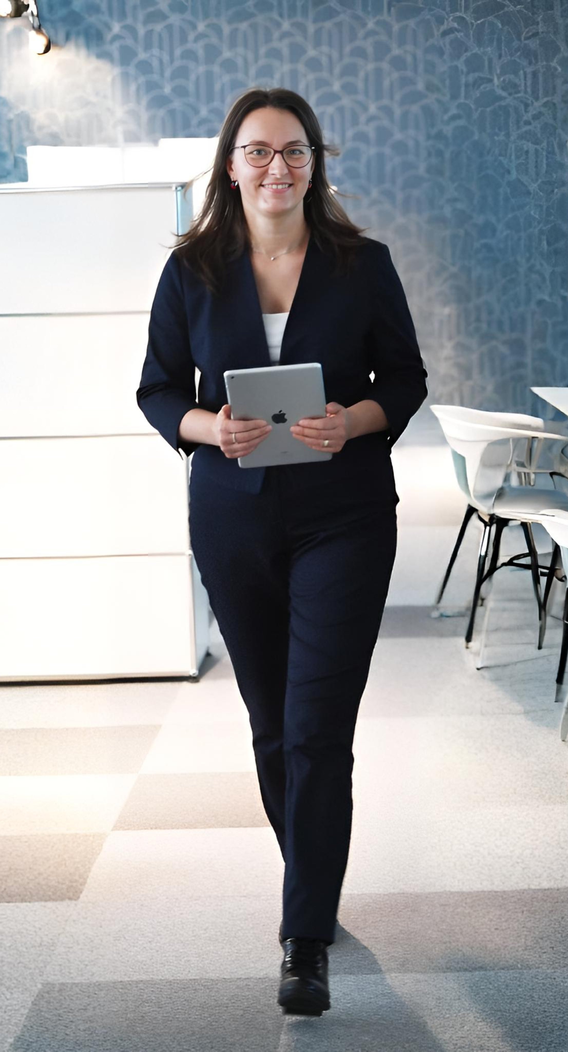 Manuela Langos sitzt lachend auf einem grauen Stuhl